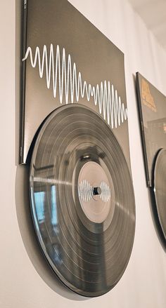 an old record player is hanging on the wall next to two other vinyl records that have been cut out