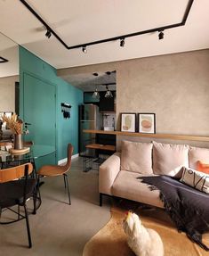 a living room filled with furniture next to a dining room table and chairs in front of a blue wall