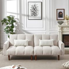 a living room with a white couch and rug on the floor in front of a fireplace