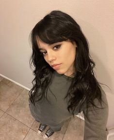 a woman with long black hair sitting on the floor