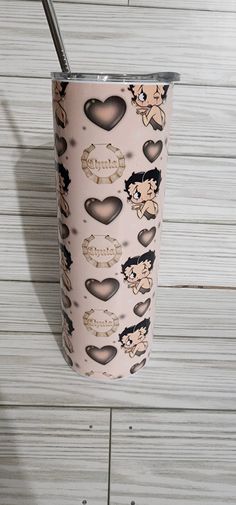 the tumbler cup is decorated with hearts and other things on it's side