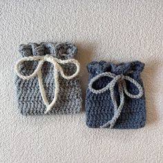 two crocheted bags sitting on the floor next to each other, one with a bow