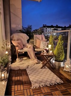 the balcony is decorated with candles, plants and rugs for relaxing in the evening