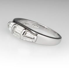 This wonderful ring is accented with two (2), channel set, straight baguette cut diamonds and four (4), channel set, tapered baguette cut diamonds. The ring measures 5.4mm at the top, rises 4.7mm above the finger, tapering to 1.9mm wide and 1.1mm thick at the base of the shank. This ring is currently a size 7.5. One tapered baguette diamond is chipped. Channel Set Baguette Rings For Anniversary, Baguette Channel Set Rings For Anniversary, Formal Baguette Channel Set Rings, Channel Set Emerald Cut Platinum Diamond Ring, Platinum Emerald Cut Channel Set Diamond Ring, Emerald Cut Channel Set Platinum Diamond Ring, Classic Diamond Ring With Channel Set Baguette Cut, Classic Channel Set Baguette Cut Diamond Ring, White Gold Diamond Ring With Channel Set Baguette Cut