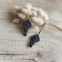 a pair of earrings with beads hanging from it's ear wires on a piece of wood