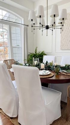 the dining room table is set with white linens and place settings for four people