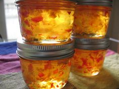 three jars filled with yellow liquid sitting on top of a table next to a window