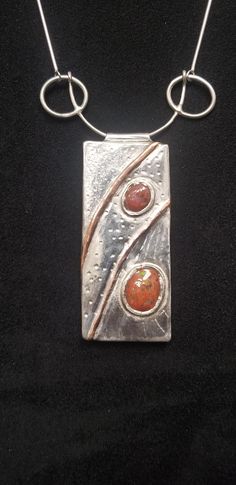 "A Box Style pendant with Sterling, Fine Silver, Copper, and Boulder Opal.  It is suspended on a 16\" chain.  The idea that the box may contain more than than the opals, tickles the imagination. What lies beneath the ripples of water, where the stones rest in the stream? Opals and silver have long been associated with feminine energies and emotion. Copper symbolized energy and movement, together they represent both a moment in time and the passing of time.  This piece is versatile, dressing up a simple blue or black shirt, or a spicing up a low cut evening gown. In every way as unique as the wearer." Unique Rectangular Sterling Silver Necklace, Unique Sterling Silver Rectangular Necklace, Modern Cabochon Necklaces For Gifts, Opal Necklaces With Polished Finish As Gift, Unique Rectangular Gemstone Necklace, Opal Necklace With Polished Finish For Gift, Artisan Opal Necklaces As Gifts, Artisan Opal Necklaces For Gifts, Metal Clay Pendant