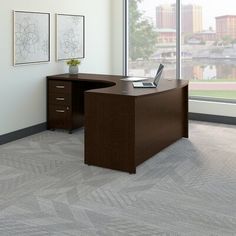 an office desk with a laptop on it in front of a large window overlooking the city