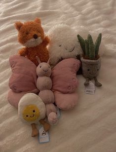 three stuffed animals are sitting on a bed with a plant and potted cacti