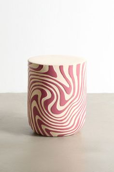 a pink and white vase sitting on top of a table next to a wall in the background