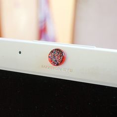 a close up of a laptop with a red and black speckled button on it