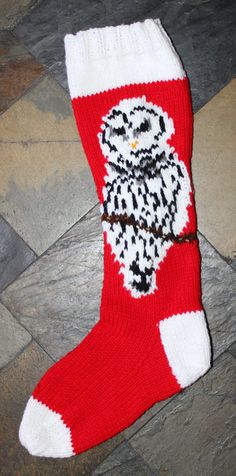 a red and white knitted christmas stocking with an owl on it's side