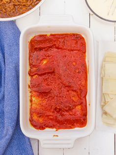 a casserole dish filled with sauce next to other dishes on a white table