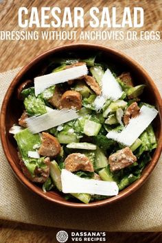 a bowl filled with salad sitting on top of a wooden table next to a napkin