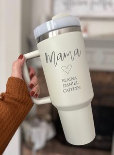 a woman holding a white coffee cup with the words mama on it