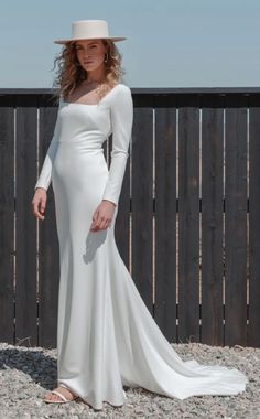 a woman in a white dress and hat posing for the camera with her hands on her hips