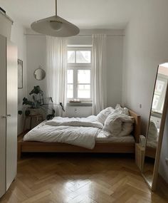 a bed sitting in the middle of a bedroom next to a window with white curtains