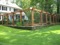 a fenced in garden area with grass and rocks on the ground near a house