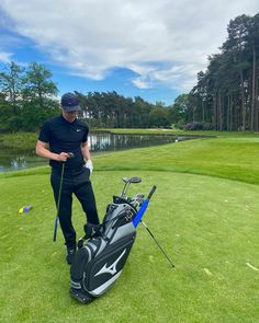 a man standing next to a golf bag on top of a green field