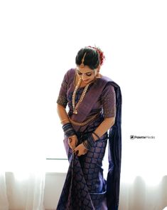 a woman in a blue sari is standing near a window