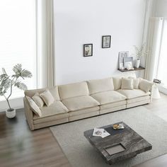 a living room filled with furniture and large windows next to a wooden floor covered in white rugs