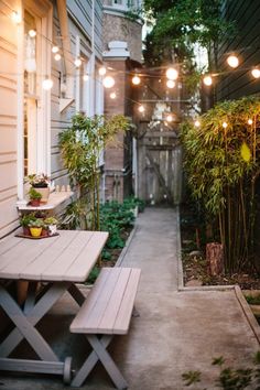 an outdoor patio with lights strung from the ceiling and wooden benches in front of it