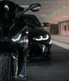 two motorcycles parked next to each other in a parking garage with green lights on them