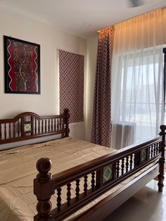 a large bed sitting next to a window in a room with curtains on the windowsill