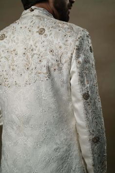 Editor's Note Featuring our work of art in our white all over hand-embroidered sherwani set. The foundation is crafted using machine embroidery adorned with tone on tone thread serving as the base texture, while the second tier showcases highlighting with 3D brass elements, dabka and zari threads. Fabric: Linen silk Color: Ivory, gold Components: Sherwani, kurta and churidar Occasion: Groom Fit: Regular Note: Product colour may slightly vary due to photographic lighting sources Care: Dry clean o Luxury Cotton Sherwani For Puja, Luxury White Sherwani With Resham Embroidery, Luxury White Sherwani For Eid, Luxury White Sherwani For Ceremony, Luxury Cream Raw Silk Sherwani, Luxury Cotton Silk Sherwani With Chikankari Embroidery, Luxury Embroidered Cotton Silk Sherwani, Luxury Cotton Silk Sherwani With Gota Work, Luxury Off-white Sherwani With Dabka Work