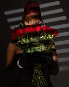 a woman with red hair holding flowers in front of her face