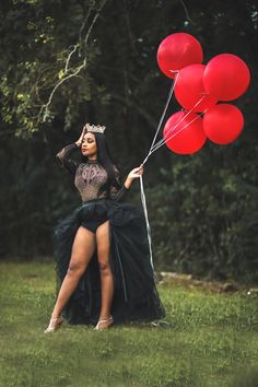 a woman in a black dress holding red balloons