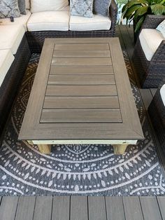 an outdoor living area with couches, tables and rugs on the decking