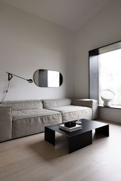 a living room with a couch, coffee table and large mirror on the wall above it