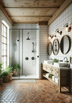 a bathroom with two sinks, mirrors and a walk in shower next to a window