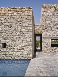 an outdoor swimming pool with stone walls and doors leading to the water's edge