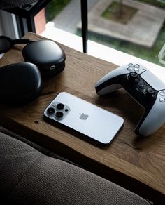 an iphone and controller sitting on top of a wooden table next to each other,