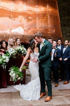 a bride and groom kissing in front of their wedding party