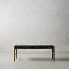 a bench sitting in front of a white wall with a black leather seat on it