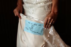 a woman in a white dress is holding a blue piece of cloth with writing on it