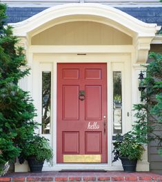 a red front door with two potted plants on the side and an arched doorway