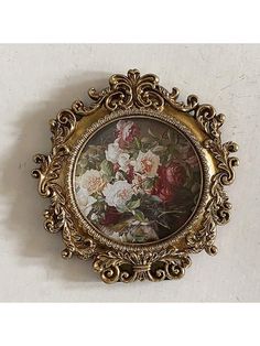 an ornate gold frame with flowers painted on the wall behind it is shown in front of a white background