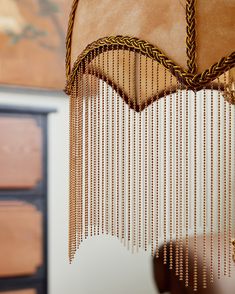 a close up of a lamp with beads hanging from it's sides and a wooden dresser in the background