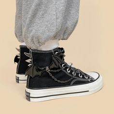 High-top black canvas sneakers featuring bold bat wings and spike details. Perfect for making a statement, these shoes combine unique design elements with a sturdy white rubber sole for daily wear. Chain detail with bat wings at side Canvas fabric Lace up at top Spiked detailing at back Cotton lining Black Canvas Sneakers, Gothic Women, Fall Sweaters For Women, Crop Pullover, Denim Hoodie, Jogger Pants Casual, Black Punks, Black High Tops, Patchwork Jeans