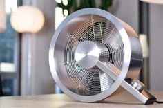 a metal fan sitting on top of a wooden table