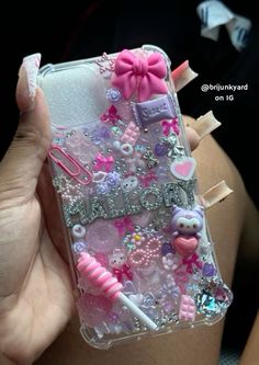 a person holding up a cell phone case with some decorations on it