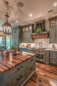 a large kitchen with wooden floors and green cabinetry, along with an island in the middle