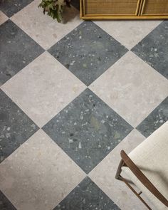 a chair sitting on top of a checkered floor next to a dresser and cabinet