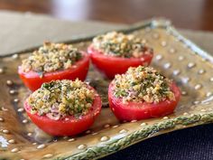 four tomatoes with seasoning on them sitting on a metal platter, ready to be eaten