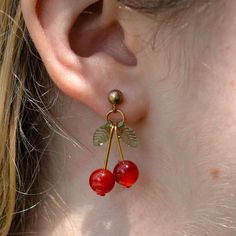 Add a playful touch to your look with these handmade Cherry Carnelian Earrings with Green Leaf Accents. These delightful earrings feature vibrant red carnelian beads shaped like cherries, complemented by delicate acrylic green leaf accents. The combination of the deep red and fresh green creates a charming and unique design that's perfect for any occasion. Crafted with care and attention to detail, these earrings are a wonderful addition to any jewelry collection. Features: - High-quality gold colored stainless steel earrings - Genuine 8mm red carnelian beads - Acrylic green leaf charms - Handcrafted with attention to detail - Earring length approximately 1.25 inches - Earring weight approximately 3 grams per earring Embrace the fun and whimsical style of these cherry earrings. They make a Cherry Beaded Earrings, Donuts Earrings, Carnelian Earrings, Cherry Earrings, Fruit Jewelry, Fruit Earrings, Carnelian Beads, Natural Stone Jewelry, Whimsical Fashion